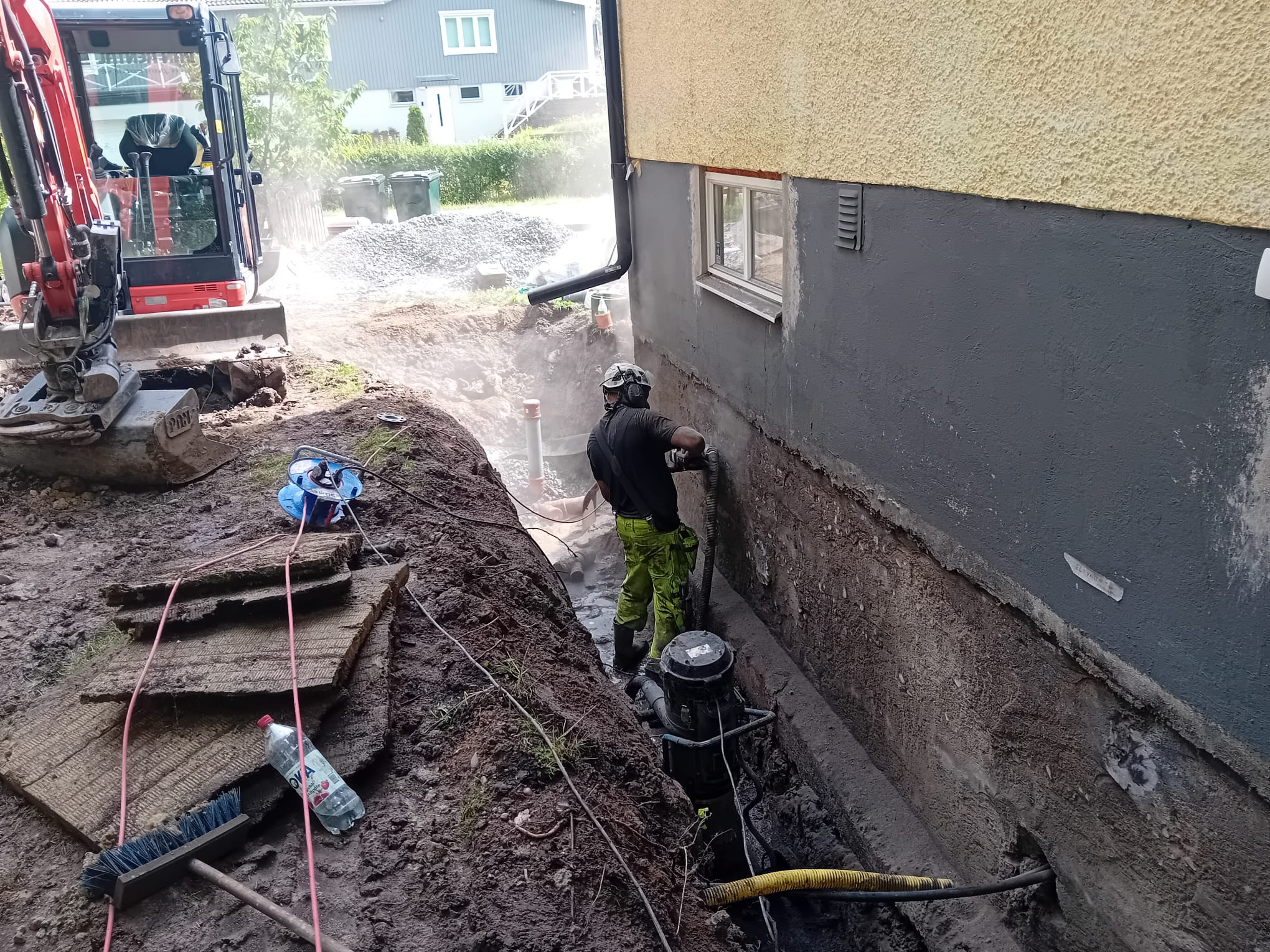 Schaktning tätt mot grundmuren med grävmaskin i Tullinge